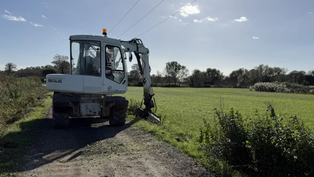 Tractopelle Mécalac équipé d’une épareuse pour l’entretien des bordures de prairie de foin de Crau